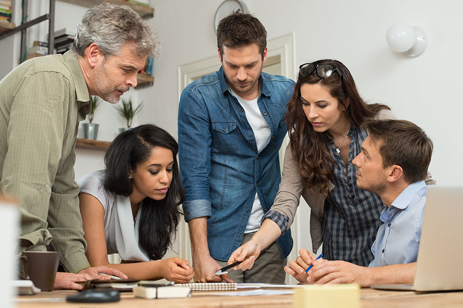 Five educators discussing ideas at a table in the staffroom.